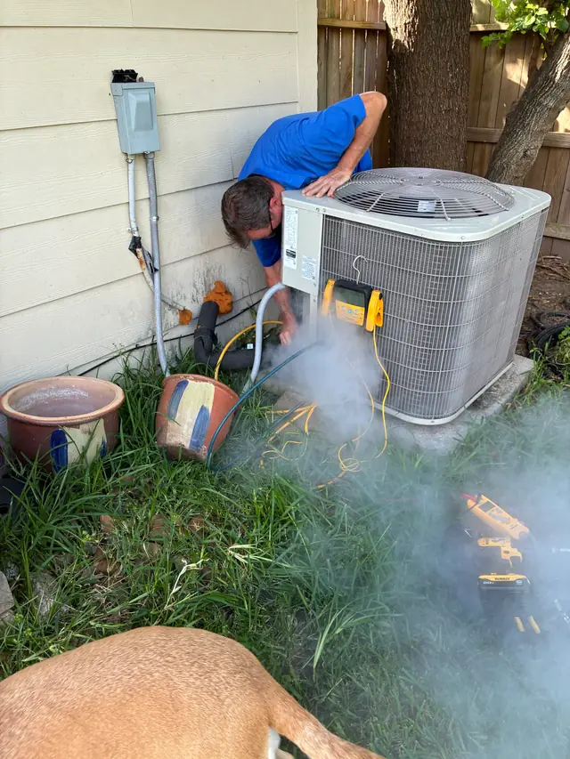 Reid's technician working at a residential condenser unit beside the house